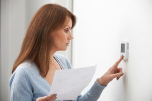 Woman Adjusting Thermostat for geothermal HVAC system